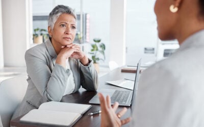 Employee speaking during a workplace meeting about race-based employment practices while managers react, illustrating Title VII retaliation and affirmative action disputes.